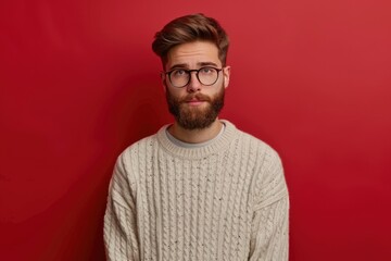 Fototapeta premium Serious young man in glasses and sweater on red background.