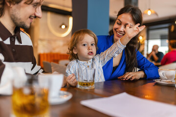 Mother, father and their baby boy sitting at the restaurant.