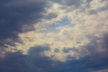 Sunlight breaks through gray storm clouds, revealing skies, celestial landscape with storm clouds