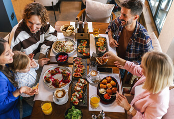 Family gathered in a restaurant to eat delicious food. They eat a variety of tasty foods.