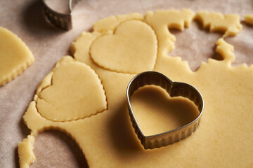 Cutting out heart shapes from rolled out dough to prepare traditional Linzer Christmas cookies