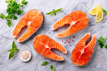 Salmon steaks, fillet with herbs and spices. White marble background. Top view.