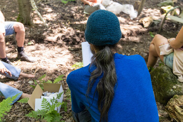 Herbalist is taking notes during an outdoor workshop in the woods, learning about medicinal plants and their uses. Selective focus