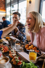 Friends feeding eachother with delicious food in a restaurant.