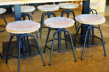 Black metal structure wooden stools, seats covered with faux fur rug. Cafe in Tallinn, Estonia, Europe. Cozy atmosphere. Brown and beige colors