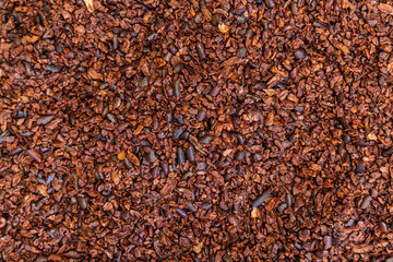 Lot of crushed cocoa beans forming a background, waiting to be processed by a chocolatier. Selective focus