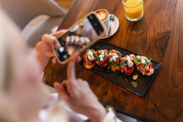 Woman influencer taking pictures of food in a restaurant. Social media. Food and drink concept.
