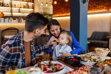 Family of three eating in a restaurant delicious food. Food and drink concept.