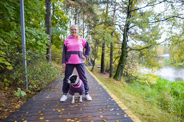 A woman on a walk with a dog. A dog in a fashionable jacket and glasses, training