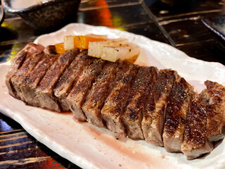 Close up of medium rare A5 steak on white plate.