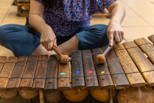 Musician sitting cross legged on the floor and playing a wooden xylophone with mallets