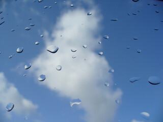 After rain, blue and white sky with raindrops on window glass after downpour - natural background....