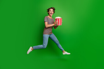 Full length portrait of impressed energetic person jump hold popcorn isolated on green color...