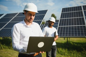 Two engineers are conducting outdoor inspection of solar photovoltaic panels