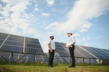 Two engineers are conducting outdoor inspection of solar photovoltaic panels