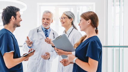 Smiling group of medical staff discussing in clinic corridor