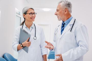 Doctors working in hospital and discussing medical reports in corridor