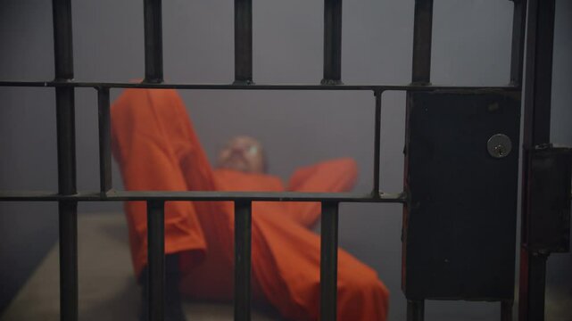 Man relaxing in jail cell through bars