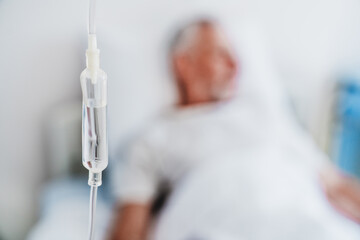 Close up shot of medicine in and iv drip and patient on background in hospital room