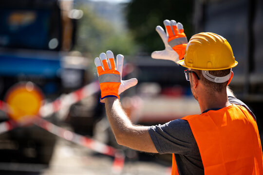Construction worker directing traffic near work zone during bright sunny day, ensuring safety on busy road