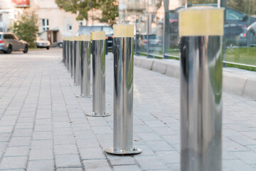 Polished Silver Bollards Line a Paved Pathway in Urban Setting
