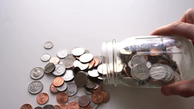 A coin jar with US coins tipping over in slow motion