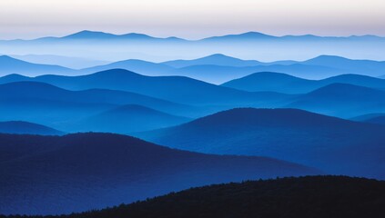 Obraz premium The early morning light casts a gentle blue hue over layered mountain ranges, creating a calming and peaceful atmosphere