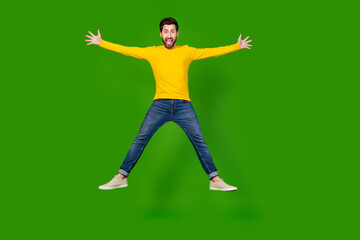 Full body photo of attractive young man jump spread hands legs dressed stylish yellow clothes isolated on green color background