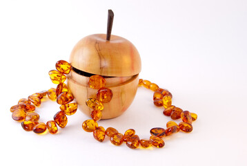 Amber necklace with wooden apple box on white background.