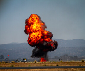 A dramatic explosion of military munitions with a ball of orange fire