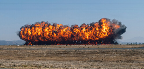 A dramatic image of a row of fire created by a munitions explosion with thick black smoke