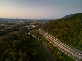 Obraz premium Aerial view of Sava river at sunset, with cars and trucks passing next to the embankment