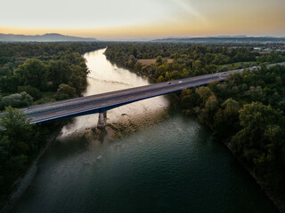 Obraz premium Aerial view of Sava river bridge at sunset, with cars and trucks crossing the river