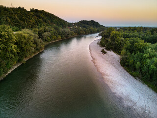 Fototapeta premium Aerial view of Sava river shoreline at sunset, with both embankments overgrown in dense forest