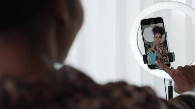 Rear view behide woman influencer shoot live stream vlog video review clothe crucial social media or blog. Girl with apparel studio lighting for marketing recording session broadcasting online