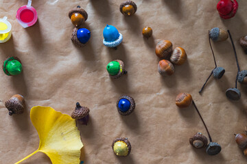 Top view of acorns, nuts and ginkgo leaf painted with colorful paints. Autumn DIY. Christmas tree decoration idea