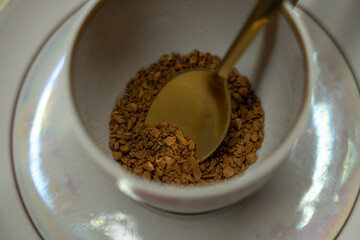 A spoonful of coffee in a mug on a saucer on a yellow background. Close up