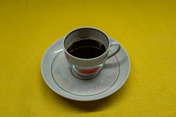 Instant coffee in a mug. A mug in a saucer on a yellow background. Top-down view
