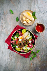 Mixed green leafy summer salad with Japanese soba buckwheat noodle, honeydew melon and peppermint served as top view with sweet sour chili dressing in a design plate
