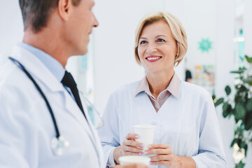 Happy doctors having coffee break and talking in modern clinic