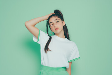 Person in white t-shirt with green edges and green sweatpants, green studio background, half-body portrait