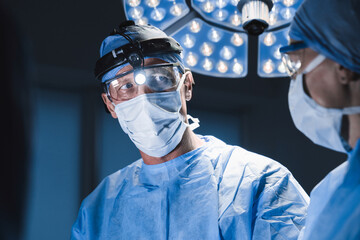 Surgeons team during operation process in surgery in dark background