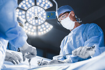 Group of surgeons at operation in operating room at hospital. Surgery, medicine and people concept.