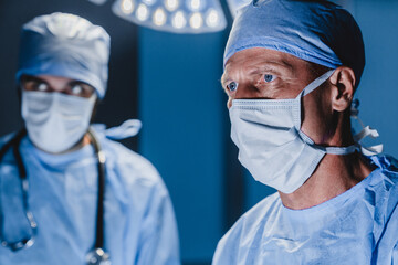 Concentrated surgeon performing surgery with his team in hospital operating room.