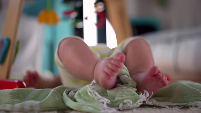 Baby lying on a play mat, focus on baby feet kicking and moving, playful and active infant exploring surroundings, early development and movement in a home environment