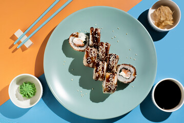 Teriyaki sushi rolls with sesame seeds on a turquoise plate