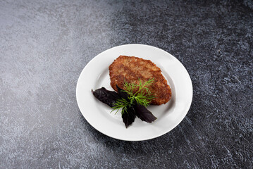 A piece of meat is on a white plate with a sprig of parsley on top