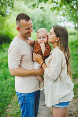 Fototapeta premium Mom, dad and little son on a walk in the park. Concept of parent time with child. Happy family couple with child in nature.