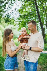 Mom, dad and little son on a walk in the park. Concept of parent time with child. Happy family couple with child in nature.