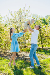 Fototapeta premium A young married couple, a man, a woman and a little son, are walking in the park. Time for a walk, mom, dad and small child.